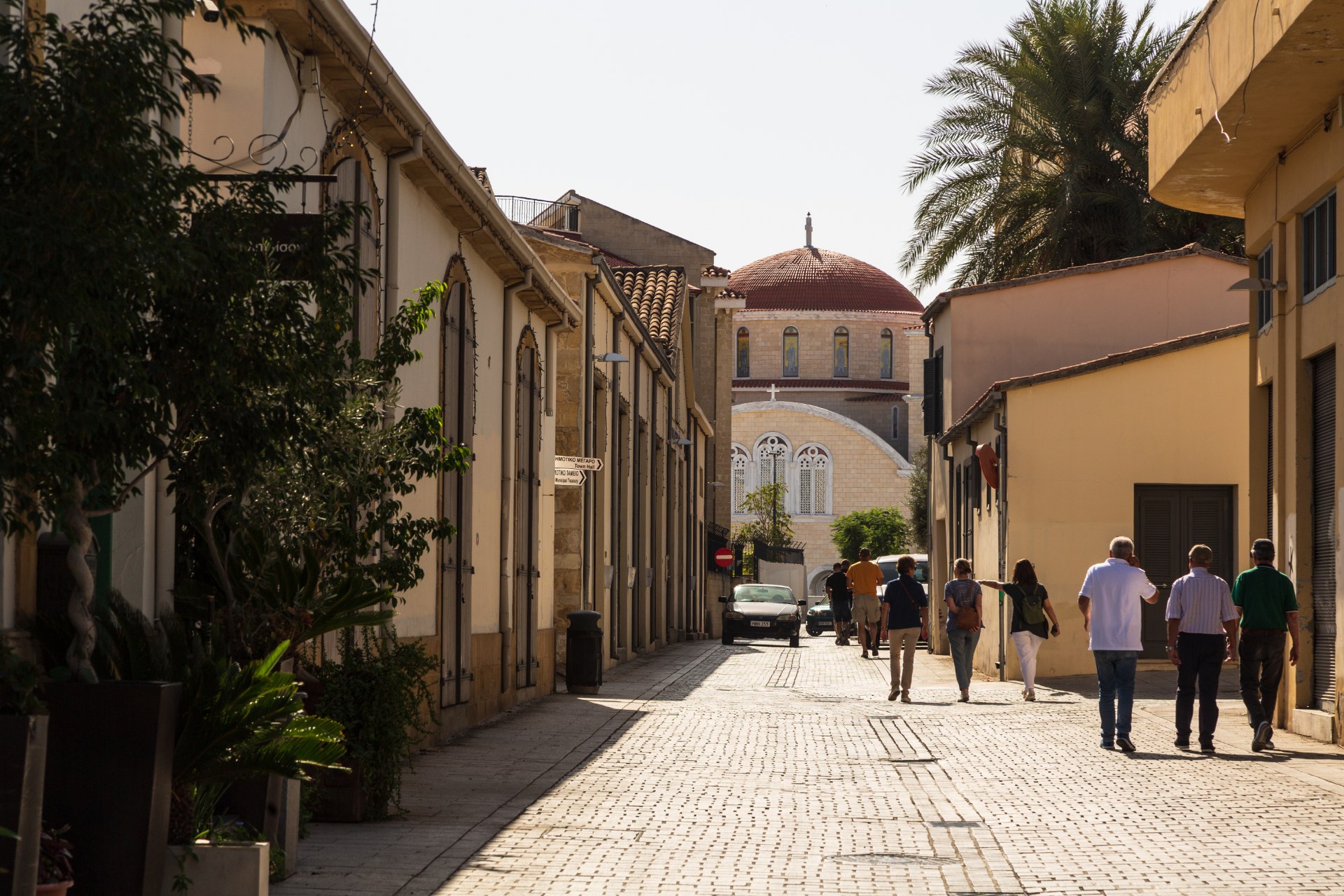Persone che camminano in una stretta via del centro storico di Nicosia, verso una cattedrale con la cupola